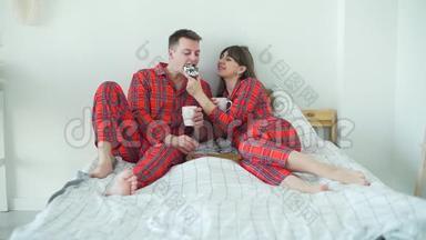 早晨在床上吃甜甜圈的年轻夫妇